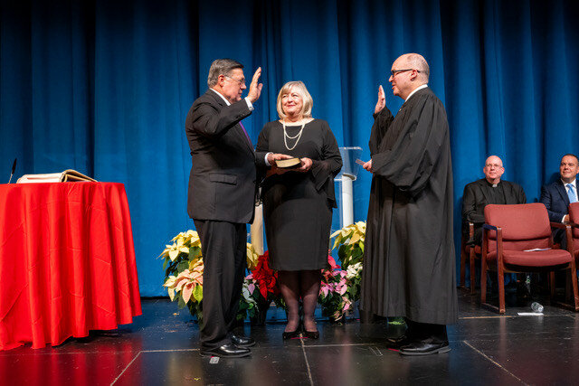 Ed Romaine takes the oath of office as county executive from Acting Supreme Court Justice James C. Hudson, while Romaine’s wife, Diane, looks on.